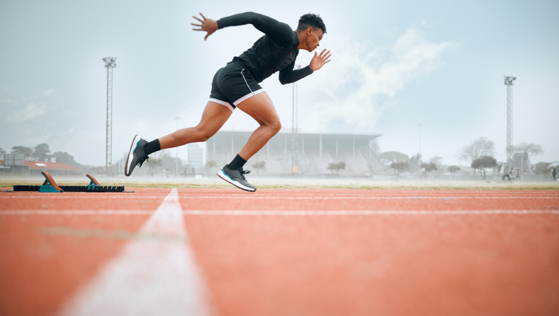 Mężczyzna startujący do biegu na stadionie lekkoatletycznym, symbolizujący energię, wydolność i aktywność fizyczną – idealne skojarzenie z suplementacją Cordycepsem.