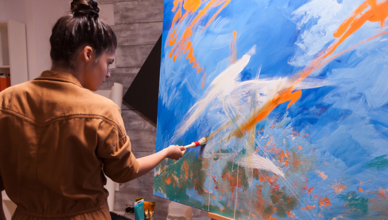 Kobieta malująca obraz w pracowni artystycznej – twórcza inspiracja i swoboda wyrażania siebie wspierana przez Lion’s Mane a kreatywność.