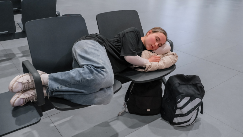 Podróżniczka śpiąca na lotnisku – adaptogeny na jet lag mogą wspierać sen i redukować zmęczenie po zmianie stref czasowych.
