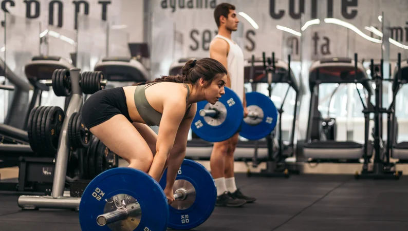 Kobieta i mężczyzna podczas treningu siłowego na siłowni – Cordyceps i Reishi dla sportowców mogą wspierać wydolność i regenerację po takim wysiłku.