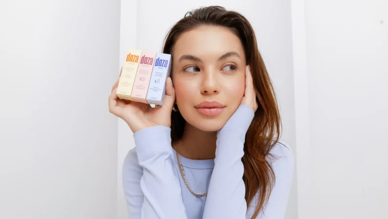 Kobieta trzymająca suplementy Doza – naturalne adaptogeny wspierające spokój, energię i zdrowy styl życia.